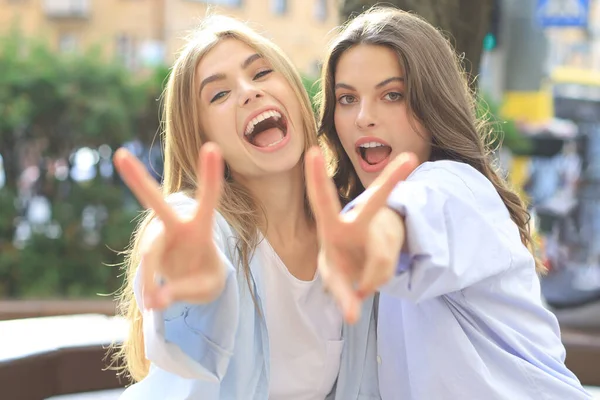 Deux jeunes femmes hipster souriantes en vêtements d'été posant dans la rue.Femme montrant des émotions faciales positives . — Photo