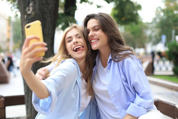 Dos amigos riendo disfrutando el fin de semana juntos y haciendo selfie en el fondo de la ciudad . —  Fotos de Stock