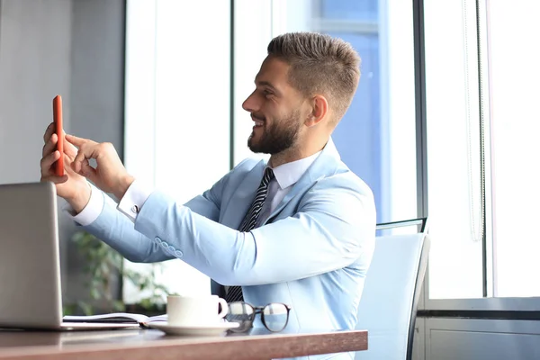 Moderno hombre de negocios sonriente se está tomando una selfie en la oficina —  Fotos de Stock