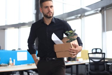 Üzgün işçi ofis malzemelerini yanında götürüyor.