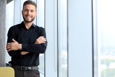 Modern iş adamı ofisin penceresinin yanında duruyor.