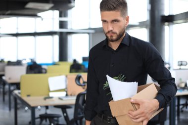 Üzgün işçi ofis malzemelerini yanında götürüyor.