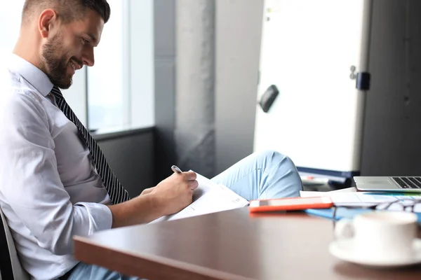 Fokuserad modern affärsman som arbetar och tar anteckningar i sitt moderna kontor — Stockfoto