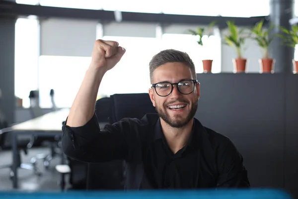 Hombre de negocios guapo está manteniendo el brazo levantado y expresando alegría en el cargo — Foto de Stock