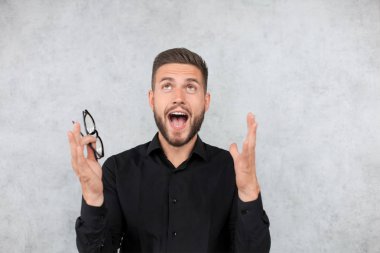 Şaşırmış genç adam gri arka plan üzerinde izole açık ağız ile kamera bakıyor