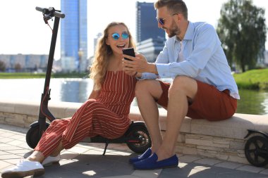 Güzel bir çift tatilde. Elektrikli scooter kullanırken eğleniyorlar. Araba kullanmaya ara veriyorlar.