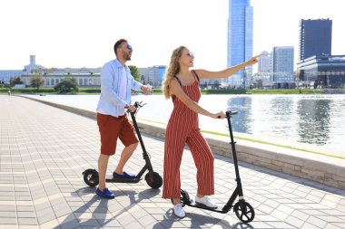 Güzel bir çift şehirde elektrikli scooter sürerken eğleniyor.