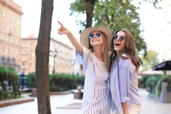 Две молодые улыбающиеся женщины-хипстеры в летней одежде позируют на улице. . — стоковое фото