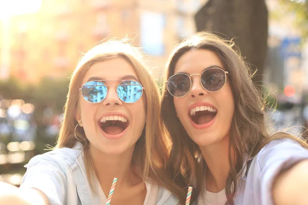 Dwóch śmiejących się przyjaciół cieszących się razem weekendem i robiących selfie na tle miasta. — Zdjęcie stockowe