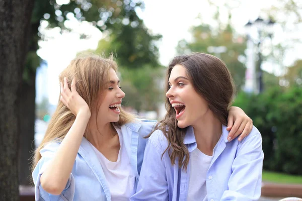 Две молодые улыбающиеся женщины-хипстеры в летней одежде позируют на улице. . — стоковое фото