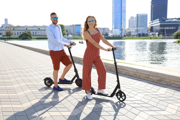 Schönes Paar, das Spaß am Fahren von Elektrorollern entlang der Stadtpromenade hat — Stockfoto