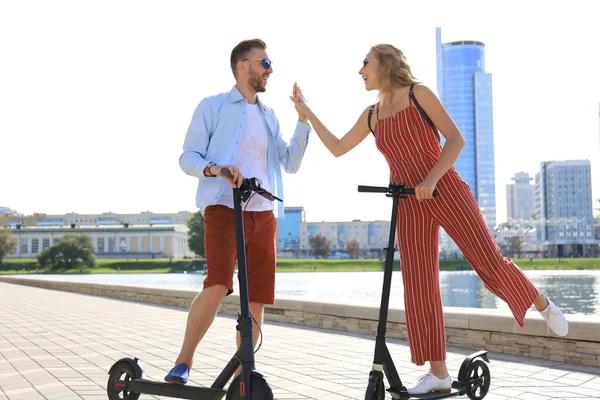 Szép pár szórakozás vezetés elektromos robogó végig a város sétányán — Stock Fotó