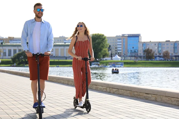 街の遊歩道に沿って楽しい電動スクーターを運転している素敵なカップル — ストック写真