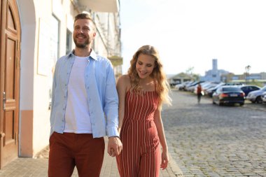 Elele ve kentin sokak içinde yürürken gülümseyen güzel genç çift