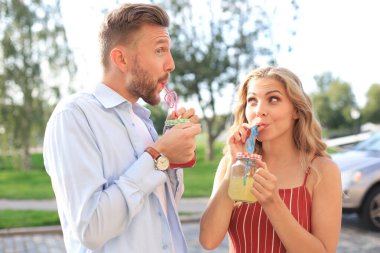 Güzel genç bir çift şehrin sokaklarında yürüyor, gülümsüyor ve taze kokteyller içiyorlar.