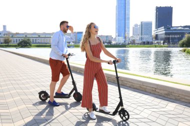 Güzel bir çift şehirde elektrikli scooter sürerken eğleniyor.