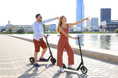 Güzel bir çift şehirde elektrikli scooter sürerken eğleniyor.