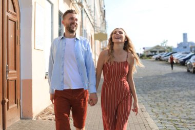 Elele ve kentin sokak içinde yürürken gülümseyen güzel genç çift