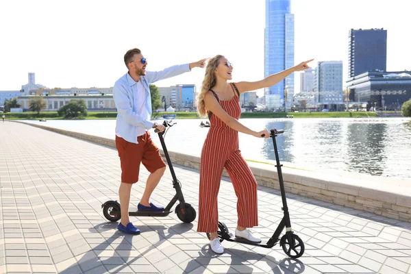 Schönes Paar, das Spaß am Fahren von Elektrorollern entlang der Stadtpromenade hat — Stockfoto