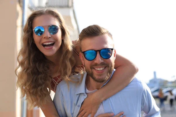 Guapo joven hombre llevando joven atractiva mujer en hombros mientras pasar tiempo juntos al aire libre — Foto de Stock
