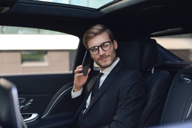 Arabada otururken telefonda konuşan düşünceli kendine güvenen işadamı.