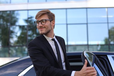 Yakışıklı ciddi genç işadamı onun rahat yeni araba içine oturan ve ofise gidiyor.