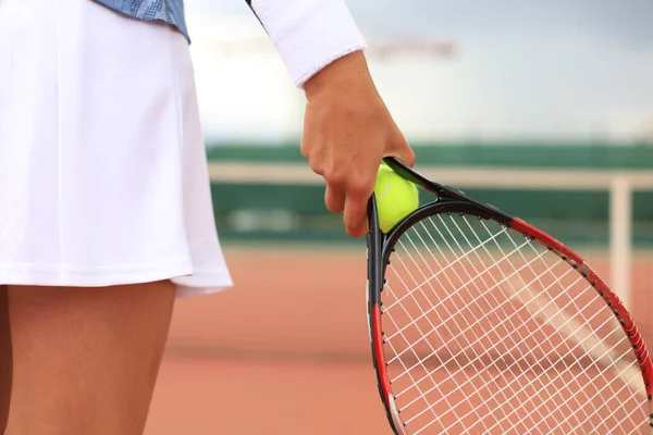 Close-up van de vrouw houdt tennisracket op de harde tennisbaan. Tennis bal in de hand van de speler. — Stockfoto