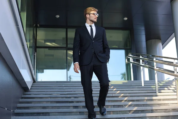 Succesvolle jonge zakenman die langs de trap buiten het kantoorgebouw loopt. — Stockfoto