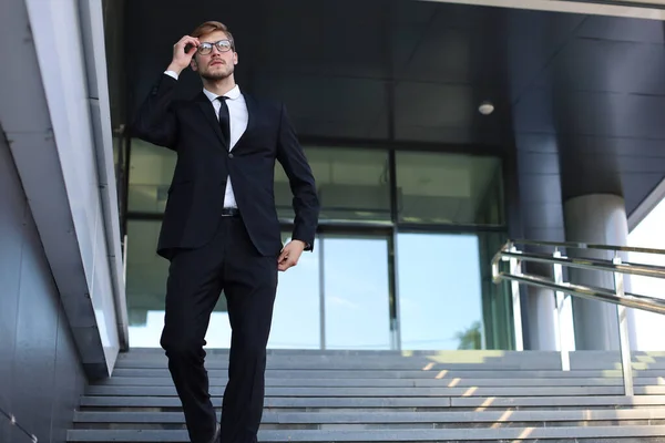 Succesvolle jonge zakenman die langs de trap buiten het kantoorgebouw loopt. — Stockfoto