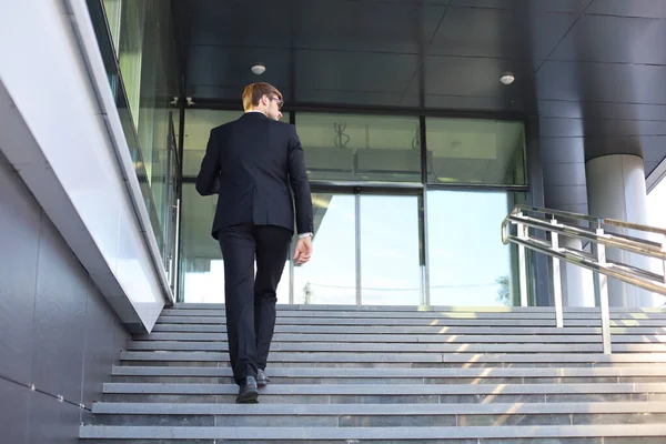 Elegante empresário de sucesso sobe as escadas do prédio de escritórios . — Fotografia de Stock