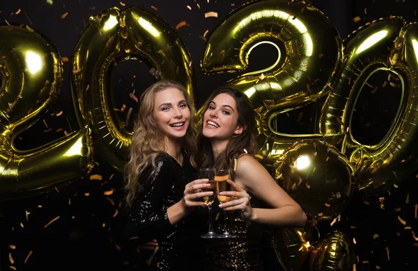 Happy gorgeous girls in stylish sexy party dresses holding gold 2020 balloons, having fun at New Year 's Eve Party . — стоковое фото