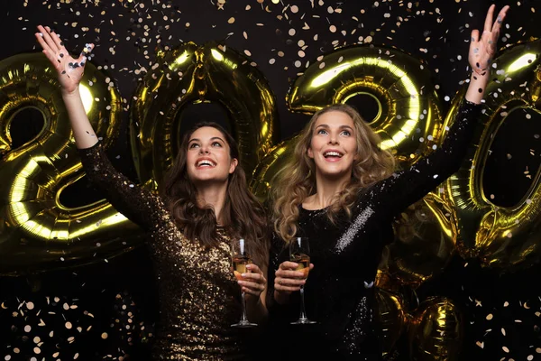 Meninas lindas felizes em vestidos de festa sexy elegantes segurando balões de ouro 2020, se divertindo na festa de Ano Novo . — Fotografia de Stock