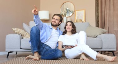 Yeni ev için tablet, yenileme ve iç tasarım ile evde oturan mutlu çift yeni ev dekorasyonu planlıyor..