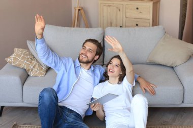 Yeni ev için tablet, yenileme ve iç tasarım ile evde oturan mutlu çift yeni ev dekorasyonu planlıyor..