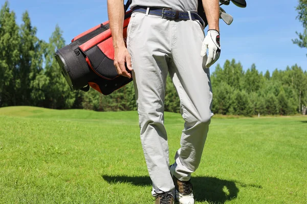 男子高尔夫球手提着高尔夫球袋走在绿草路上的剪影 — 图库照片