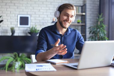 Konsantre genç serbest çalışan işadamı video konferansı için dizüstü bilgisayar kullanıyor, evde uzaktan çalışıyor.