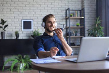Sesli mesaj kaydetmek ya da internette sohbet etmek için akıllı telefon tutan gözlüklü tatmin olmuş bir iş adamı.