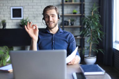 Konsantre genç serbest çalışan işadamı video konferansı için dizüstü bilgisayar kullanıyor, evde uzaktan çalışıyor.