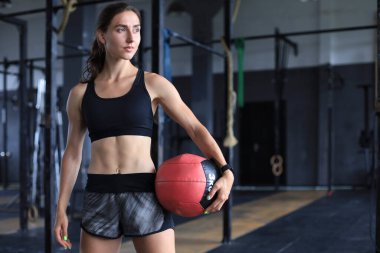 Formda spor salonunda ilaç topu taşıyan kaslı güçlü bir kadın.