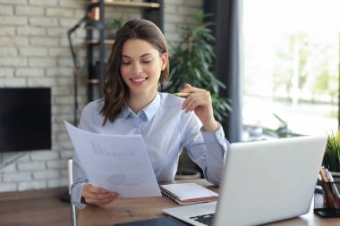 Mutlu girişimci kadın, masa başında oturup, post-paper yazışmalarında iyi haberler okuyor.