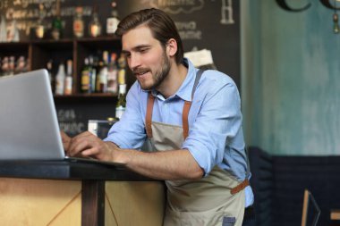 Restoran müdürü laptopta çalışıyor, kârı da sayıyor.