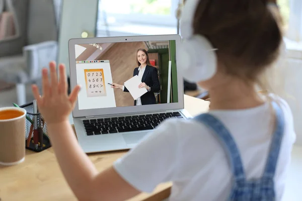 Mesafe öğrenme. Kulaklıklı neşeli küçük kız bilgisayarını kullanarak internetten e-öğrenim sistemini inceliyor.. — Stok fotoğraf
