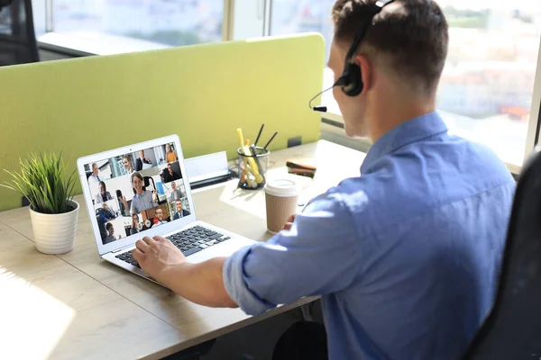 Geschäftsfrau mit Kopfhörer im Gespräch mit ihren Kollegen in einer Videokonferenz. Multiethnisches Geschäftsteam, das von zu Hause aus mit Laptop arbeitet und den Finanzbericht seines Unternehmens diskutiert. — Stockfoto