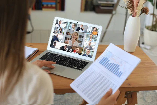 Mujer de negocios con auriculares hablando con sus colegas en videoconferencia. Equipo de negocios multiétnicos que trabajan desde casa usando el ordenador portátil, discutiendo el informe financiero de su empresa. — Foto de Stock