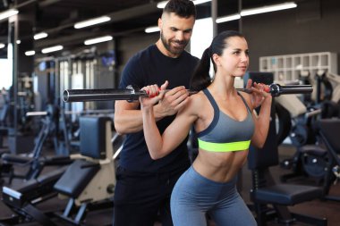 Spor salonunda halterli kadın ve erkek kaslarını esnetiyor..