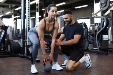 Spor salonunda müşterisiyle egzersiz yapan beden eğitimi öğretmeni.