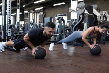 Güzel genç spor çifti jimnastik salonunda sağlık topuyla antrenman yapıyor.