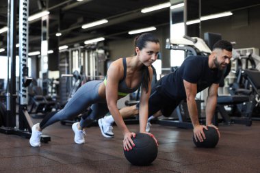 Güzel genç spor çifti jimnastik salonunda sağlık topuyla antrenman yapıyor.