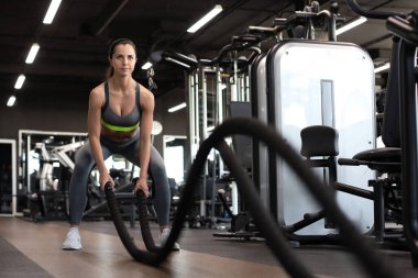 Formda bir kadın spor salonunda antrenman yaparken halat kullanıyor.