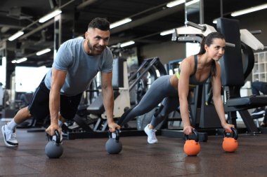 Spor salonunda şınav çeken kadın ve erkek.